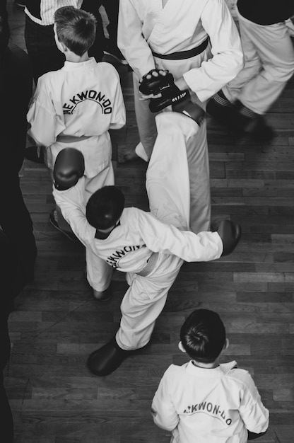 Artes marciales Taekwondo Niños con cascos y guantes kimano tradicionales Duelo deportivo Texto en blanco y negro Taekwondo es el nombre del arte marcial