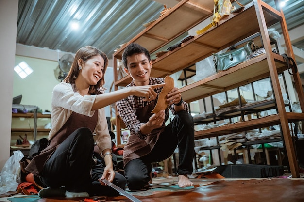 Foto artesã e artesão no chão segurando um padrão de couro para artesanato no estúdio