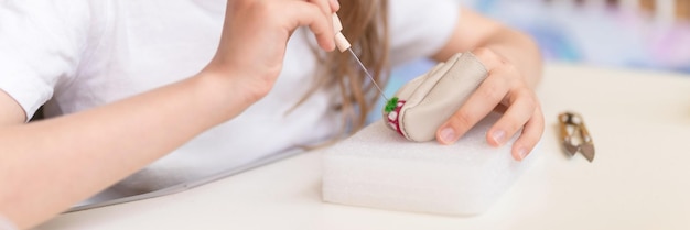 Foto artesanato de lã de feltro feito à mão com agulha garotinha artesã de nove anos com a mão faz um brinquedo criativo feito de cabelo de ovelha pessoas crianças passatempo e banner de atividade de feltragem artesanal