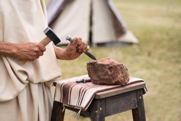 Artesanato, homem trabalhando pedra com martelo e cinzel, artesanato e arte