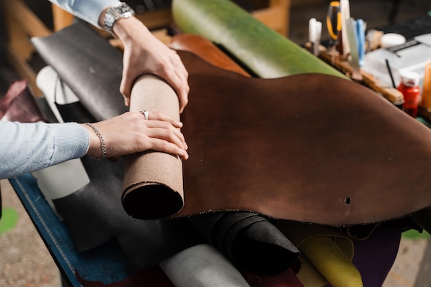 Foto el artesano del cuero toca el rollo de cuero genuino en el taller rollos de cuero genuino de diferentes colores en el taller de productos de cuero