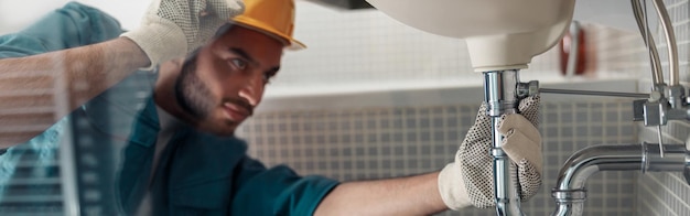 El artesano está reparando el grifo de un fregadero en el baño Concepto de mantenimiento y asistencia doméstica