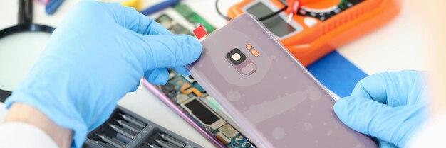 Artesano en guantes de goma cerrar la tapa del teléfono móvil en el primer taller