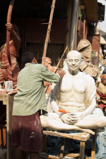 Artesano indio que produce la estatua de dios hindi en el distrito de Kumartuli de Calcuta, Bengala Occidental, India