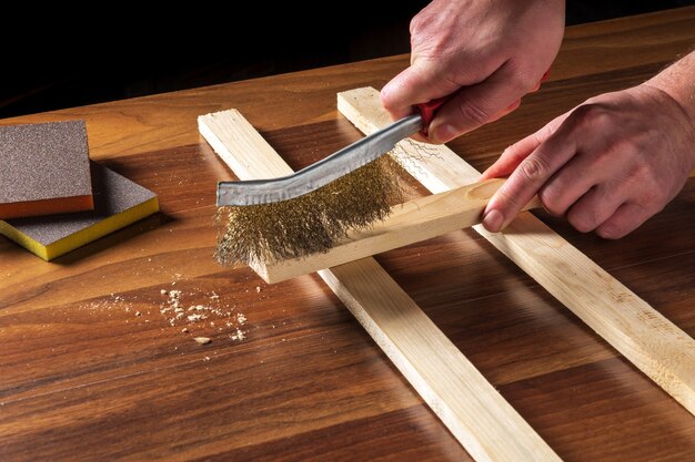 Foto el artesano limpia la tabla de madera con una herramienta abrasiva.