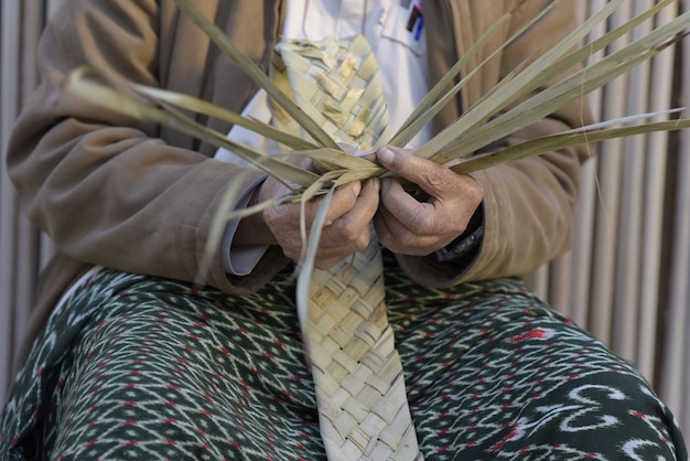Un artesano tejiendo cestas de hojas de palma.