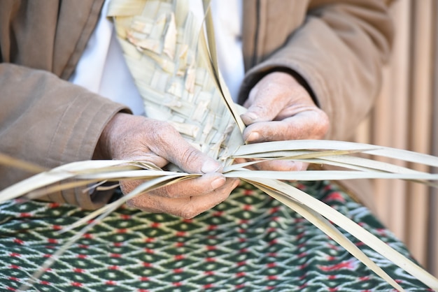 Un artesano tejiendo cestas de hojas de palma.