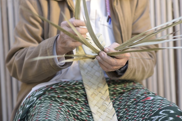 Un artesano tejiendo cestas de hojas de palma.