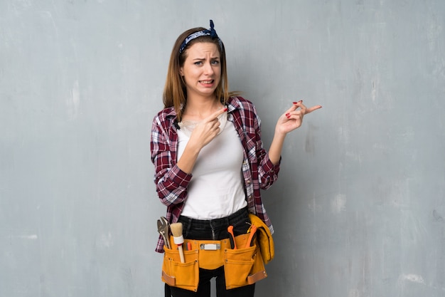 Artesanos o mujer electricista asustados y apuntando hacia un lado.