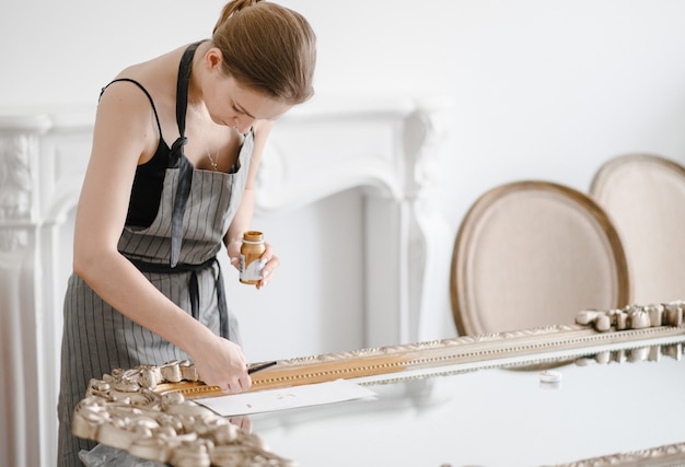 Artesão feminino mãos trabalhando em uma grande moldura de madeira