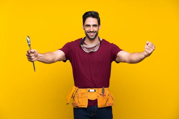 Foto artesão jovem bonito sobre fundo amarelo isolado