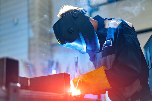 Artesão serrando metal na oficina Homem trabalhador que solda construção de metal