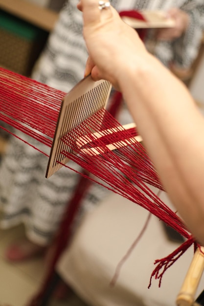 Artesão tecendo fio vermelho em tear de madeira em ambientes fechados à luz do dia Autenticidade cultural ucraniana