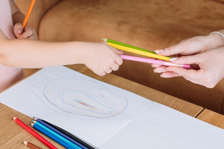 Foto arteterapia para niños. mano de niña tomando un lápiz para comenzar a dibujar una imagen. ocio artístico infantil y afición a la pintura creativa.