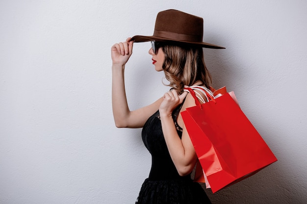 Artfrau in der Sonnenbrille mit Einkaufstaschen auf weißer Wand