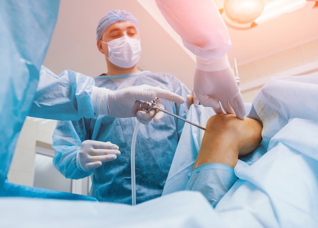 Arthroskopische Chirurgie. Orthopäden in Teamarbeit im Operationssaal mit modernen arthroskopischen Werkzeugen. Knieoperation.