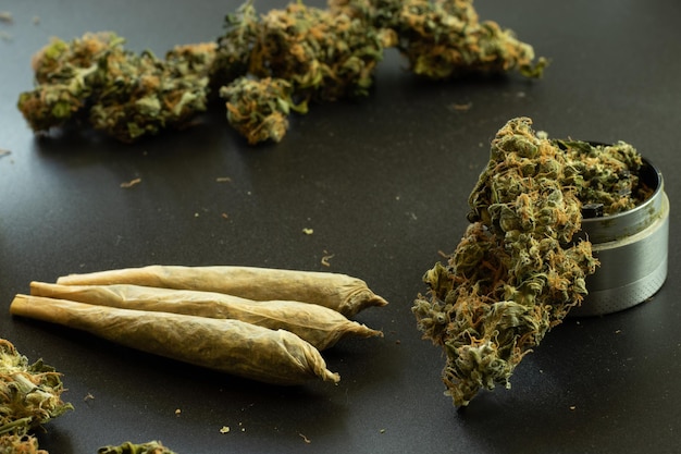 Articulaciones de malezas sobre fondo negro con cogollos de marihuana y molinillo closeup Uso legal de drogas THC