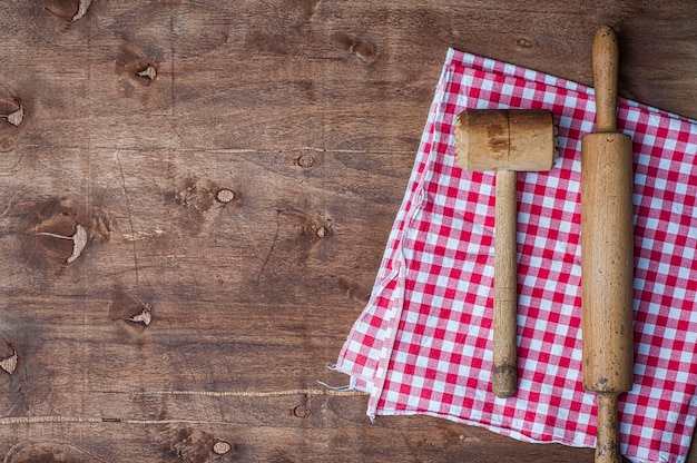 Foto artículos de cocina de madera en una servilleta roja, rodillo y martillo para batir carne