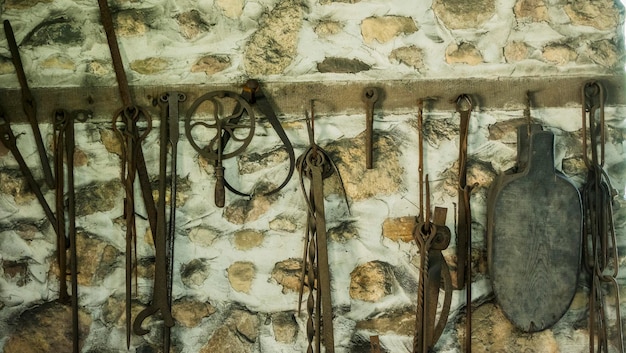 Foto artículos forjados herramientas de la antigüedad cuelgan de la pared del granero