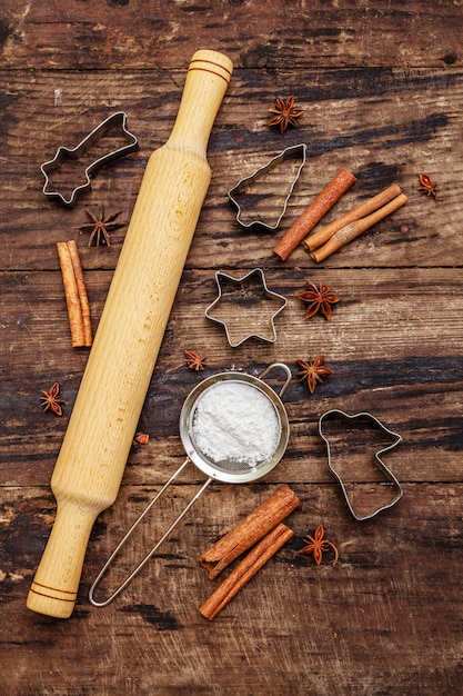 Artículos para hornear navideños, utensilios para hornear, especias, cortadores de galletas: estrellas, ángel y abeto, tamiz, azúcar en polvo y un rodillo. Viejas tablas de madera