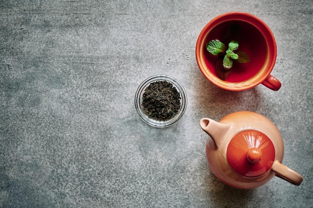 Artículos de té naranja, tetera y taza, concepto de beber té, estilizado