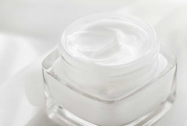 Artículos de tocador de marca cosmética y frasco de crema hidratante de crema facial de concepto spf sobre fondo de seda loción para el cuidado de la piel hidratante y cosméticos antiedad de emulsión de elevación para la marca de cuidado de la piel de belleza de lujo