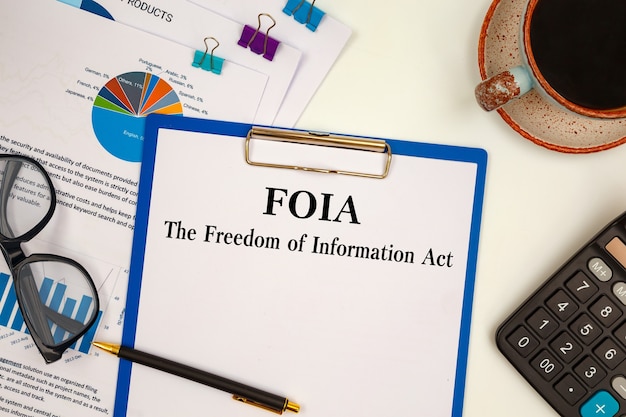 Artigo com The Freedom of Information Act FOIA na mesa, calculadora e óculos