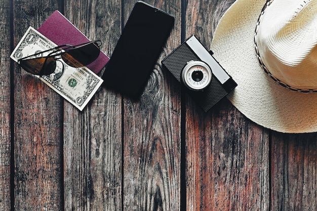 Artikel für den Sommerurlaub eine Kamera Passsmartphone Geld Hut Sonnenbrille Holzhintergrund Draufsicht mit Kopierbereich Schönes Sommerkonzept für Reisen und Sommerferien