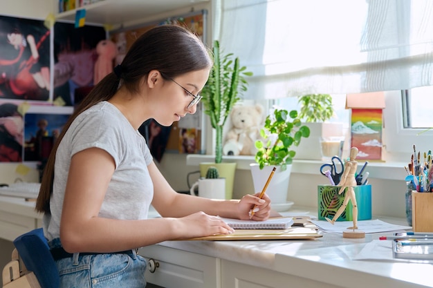 Artista adolescente creativa dibujando con un lápiz sentada en la mesa en casa usando un maniquí de madera Creatividad escuela afición ocio estilo de vida adolescencia concepto juvenil