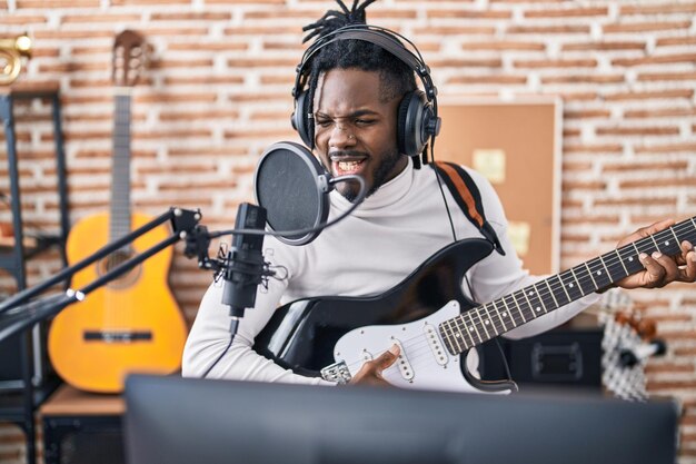 Artista afro-americana cantando música tocando guitarra elétrica no estúdio de música