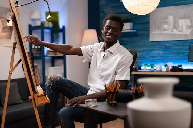 Artista afro-americano sentado em frente ao vaso de desenho de tela trabalhando em desenhar sombras usando lápis gráfico profissional. Jovem ilustrador trabalhando em masterprice criativo no atelier de arte