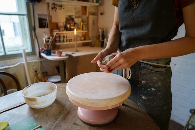 Artista de alfarería arcilla de moldeado femenino en torno ceramista en delantal trabajar con loza cruda para alfarero