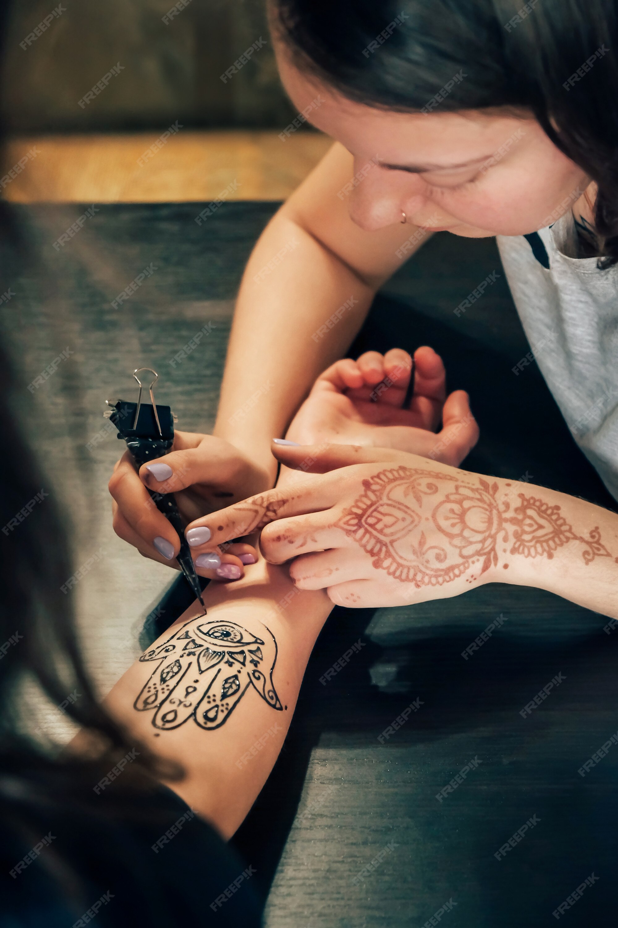 Artista aplicando tatuagem de henna mehndi na mão feminina