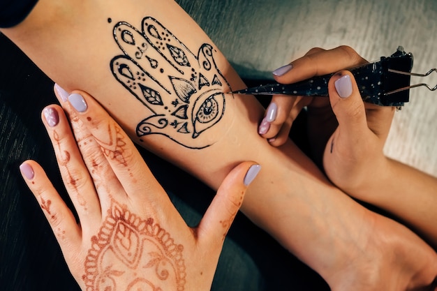 Artista aplicando tatuaje de henna mehndi en mano femenina