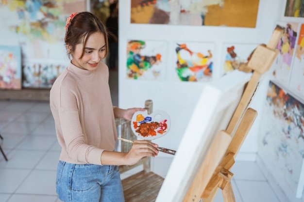 Artista asiática pintando sobre lienzo haciendo algunos proyectos de arte en su taller de estudio