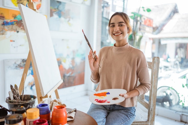 Artista asiática pintando sobre tela fazendo alguns projetos de arte em seu ateliê