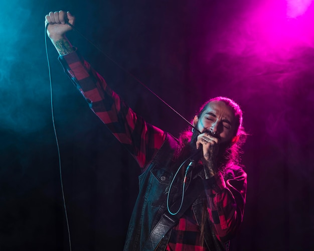 Foto artista cantando y sosteniendo el cable del micrófono.