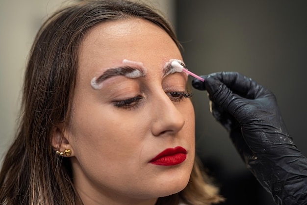 Un artista de cejas está laminando las cejas de una hermosa clienta