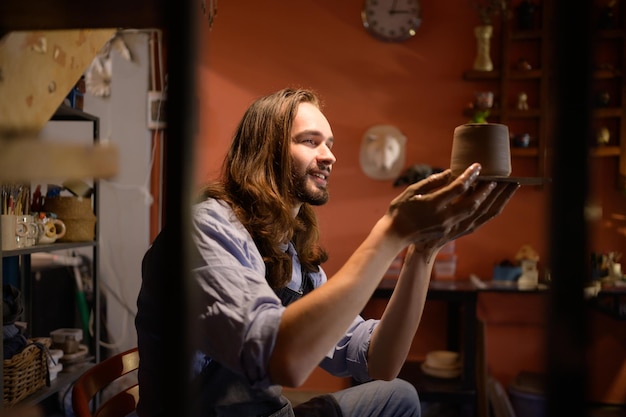 El artista de cerámica Young haciendo una pieza de arcilla moldeando con calma y meticulosidad para producir