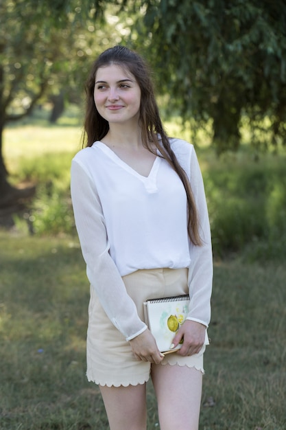 Artista chica pinta un cuadro con acuarelas en la naturaleza.