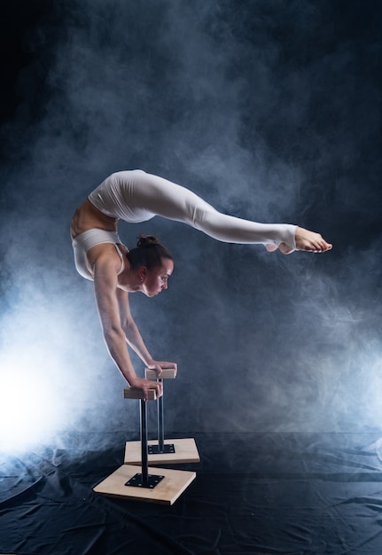 Artista de circo flexible - acróbata femenina haciendo pino en la espalda y fumador