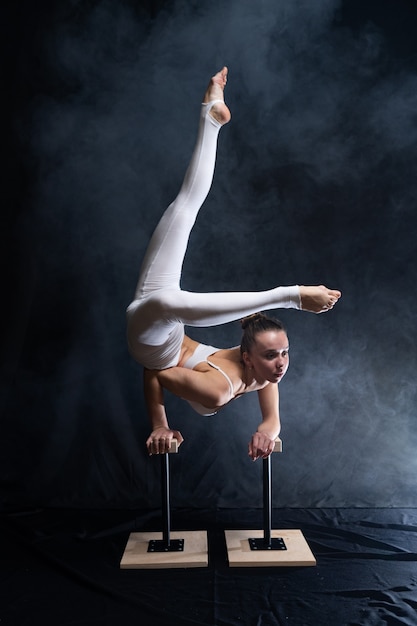 Artista de circo flexible acróbata femenina haciendo pino en la espalda y humo