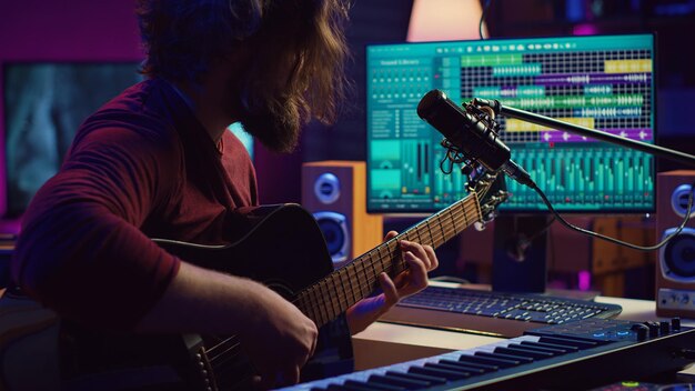 Artista componiendo una canción con su guitarra acústica en su estudio casero