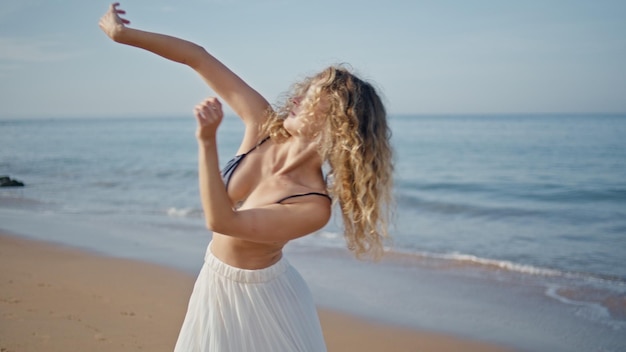 Artista contemporáneo practicando coreografía sensual en una playa soleada de cerca