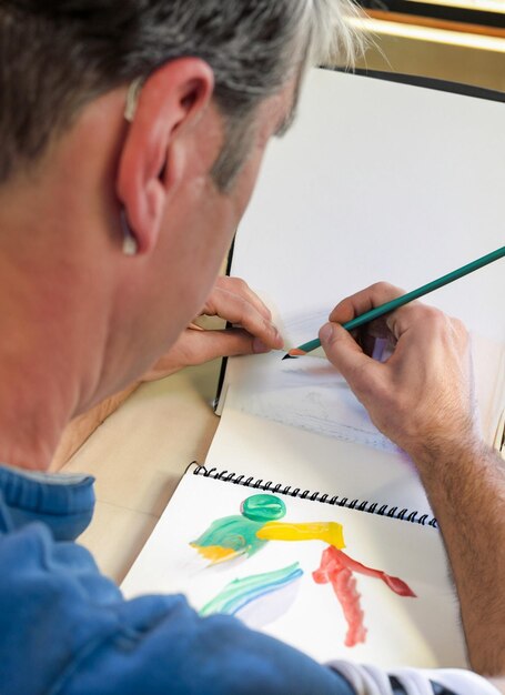 Foto un artista con un cuaderno de bocetos y lápices creando obras maestras coloridas