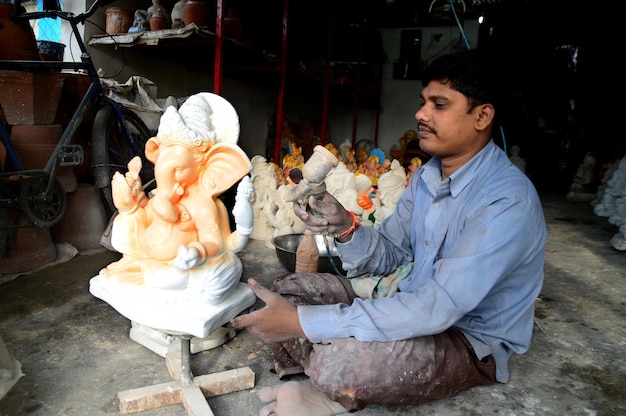 Artista dá toques finais em um ídolo do deus hindu Lord Ganesha em uma oficina de artista para o festival Ganesha