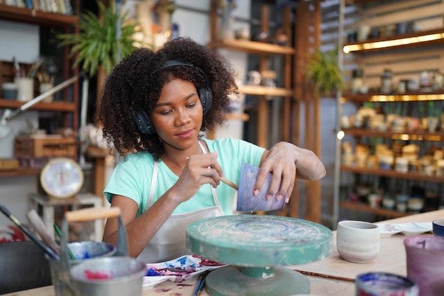 Foto artista de cerâmica pintando a superfície exterior da peça de cerâmica