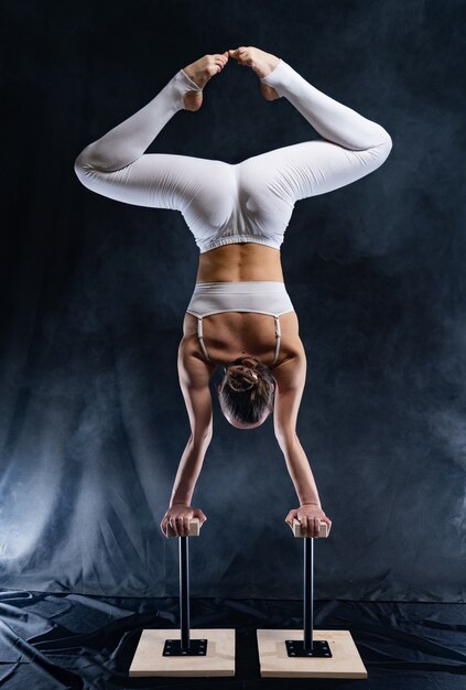 Artista de circo flexível, acrobata feminina fazendo parada de mãos