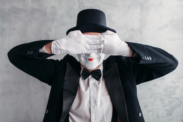 Artista de circo posando, pantomima com máscara de maquiagem branca. ator de comédia de terno, luvas e chapéu