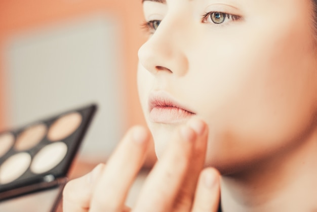 Artista de make-up fazendo maquiagem de uma linda jovem no estúdio